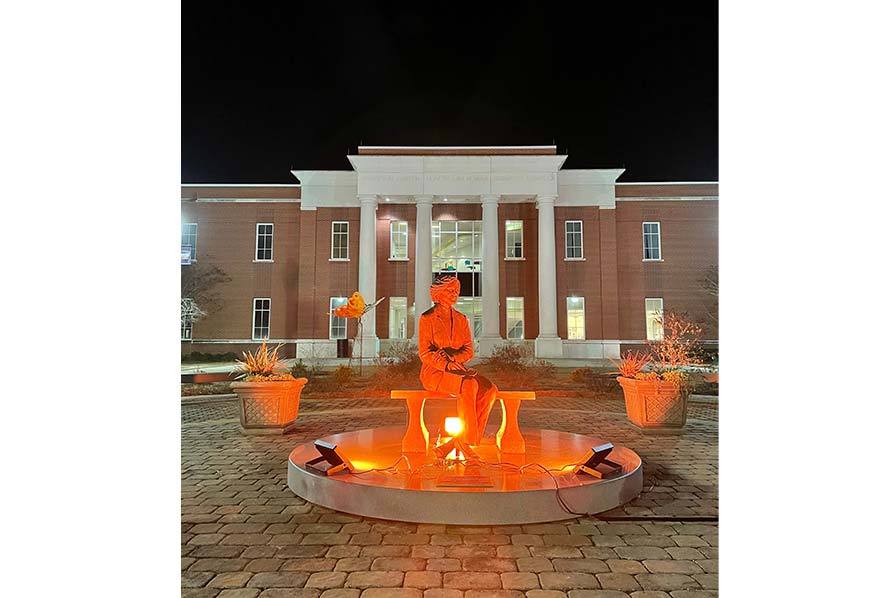 Close-up photo of the Rosalynn Carter statue illuminated with orange light.